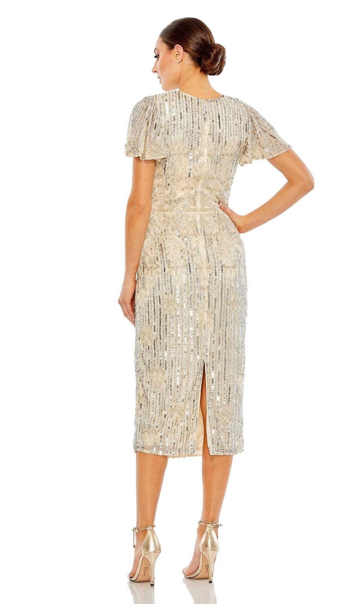 A woman stands with her back to the camera, wearing the Mac Duggal Short Semi-Formal Dress 5575—a gold sequin, knee-length, short-sleeve midi dress—paired with high heels.